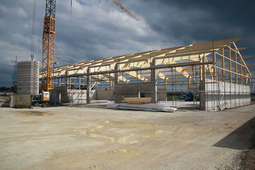 Maschinen- und Bergehalle im Bau – Stahlbetonstützen und Betonwände mit Kran