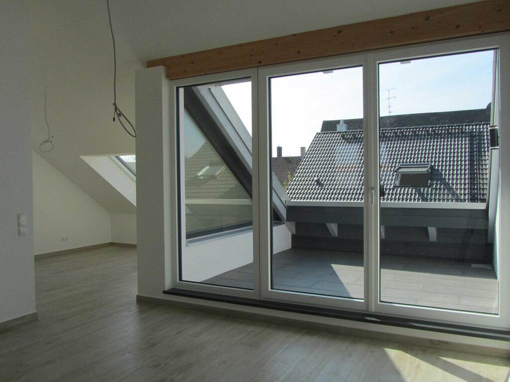 Wohnraum im Dachgeschoss-Appartment mit bodentiefer Verglasung zur Dachterrasse