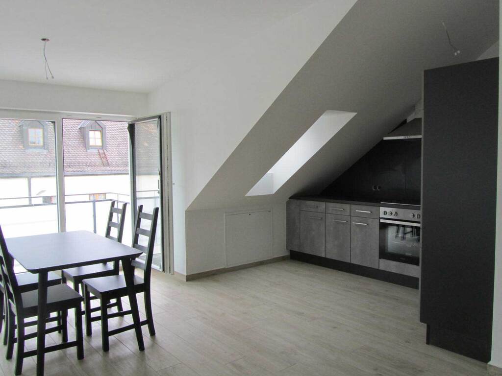 Dachgeschoss-Appartment – Essbereich mit offener Küche und Balkonzugang